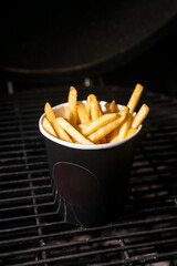 selective focus, French fries with salt and spices in a craft black mock up cup. Low Key