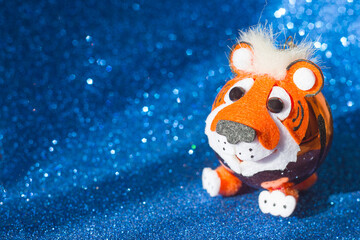 Christmas tree toy tiger symbol of the new year 2022 on a blue background with glitter, copy space for text