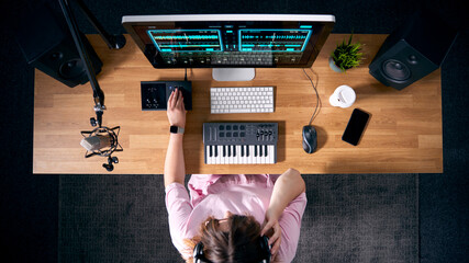 Overhead View Of Female Musician At Workstation With Keyboard And Microphone In Studio