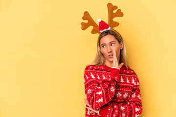Young caucasian woman wearing a christmas reindeer hat isolated on beige background is saying a secret hot braking news and looking aside © Asier