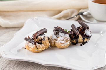 Profiteroles Italian dessert Puff pastry filled with vanilla and topped with chocolate on the table