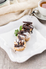 Profiteroles Italian dessert Puff pastry filled with vanilla and topped with chocolate on the table
