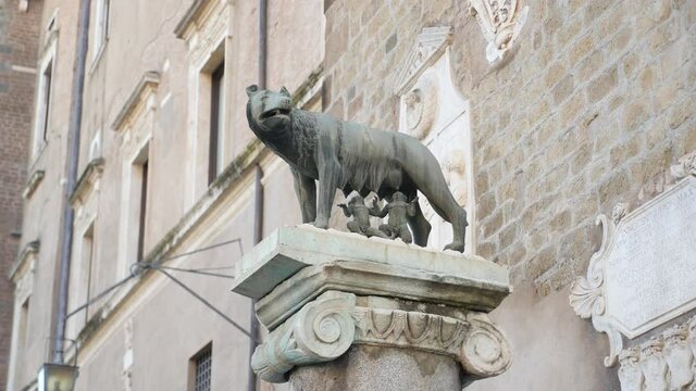 Icon of Italian capital Rome city. Statue of she-wolf on Capitoline hill against red brick wall. Twins founders of Rome city - Romulus and Remus - suckling she-wolf. 