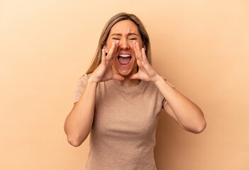 Young caucasian woman isolated on beige background shouting excited to front.