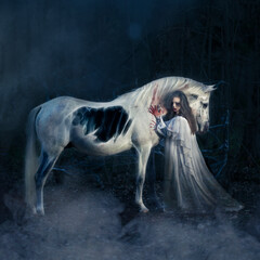 Woman in ghost dress and dead white horse in night forest