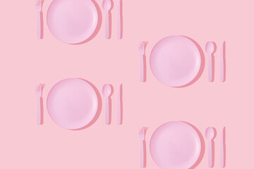 Creative pattern made with pastel pink plate, spoon, fork and knife on pastel pink background....