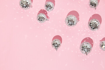 Christmas and New Year creative layout with disco ball decoration on pastel pink background. 80s or 90s aesthetic fashion holiday concept. Trendy minimal holiday idea.