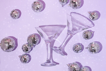 Christmas party creative layout with martini  cocktail glasses and disco ball decoration on  pastel purple background. Retro fashion aesthetic party concept. New Year or Christmas idea.