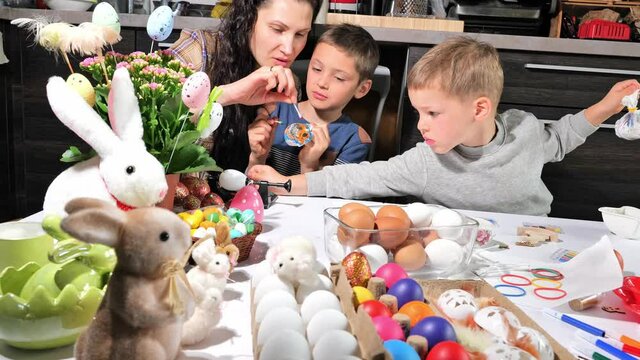 Mother and children painting Easter eggs. Happy family preparing for happy Easter day at home. Holiday and child concept
