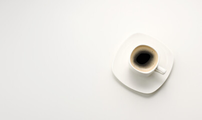 black espresso coffee in white ceramic cup with saucer on white table, top view