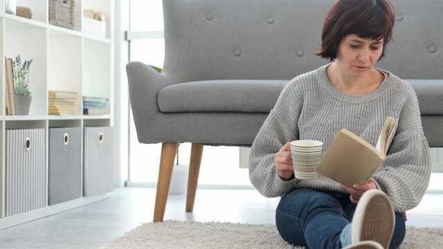 Woman reading book on a floor at home