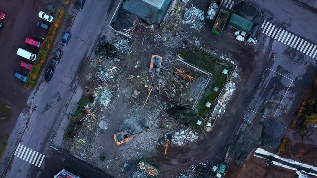 Aerial drone view rotating above diggers dismantling a urban city building
