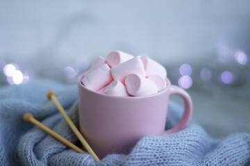 knitting needles, a cup of coffee with pink marshmallows.Christmas lights.