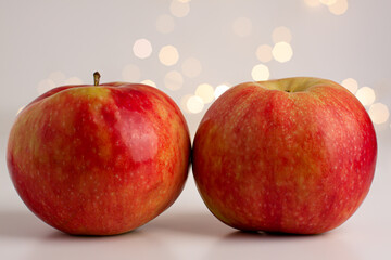 Close up of two red yellow apples on bright background with yellow gold bokeh behind. Healthy organic food, autumn mood and still life concept with copy space
