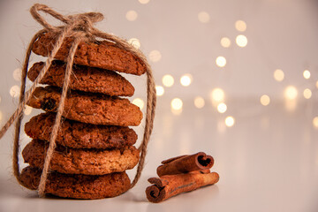 Close up of oatmeal cookies in a stack tied with brown thread and cinnamon sticks on bright...