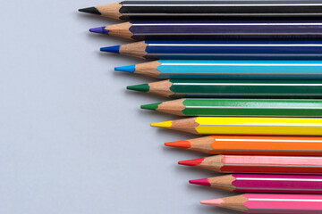 Color pencils on a light gray blue background. Top view with space for text. Back to school concept. Flat lay stationery mockup. Bright backplate for your design. Spectrum of different colors