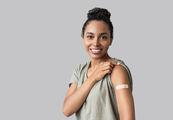 Woman smiling after receiving vaccination, young girl received a corona vaccine looking away isolated on gray background - obrazy, fototapety, plakaty