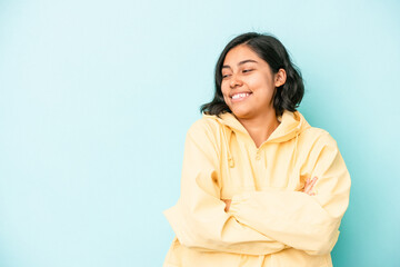 Young latin woman isolated on blue background smiling confident with crossed arms.