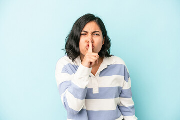Young latin woman isolated on blue background keeping a secret or asking for silence.