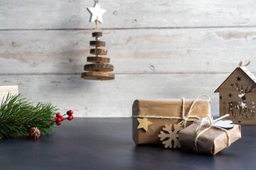 Obraz na płótnie Canvas Christmas and zero waste, eco friendly packaging. wrapped gifts in craft paper on a wooden background. ecological Christmas holiday concept, eco decor with wood