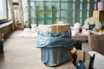 Grey clay block on desk. Female ceramist working in pottery studio. Process of creating pottery. Master ceramist works in her studio