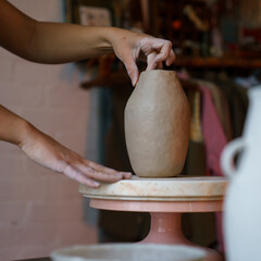 Pottery production: female artist hand shaping and sculpturing potter vase of raw clay. Woman artisan work on ceramics in studio. Art business, university master class or workshop ownership occupation