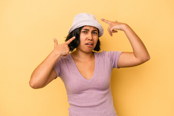 Young latin woman isolated on yellow background showing a disappointment gesture with forefinger.