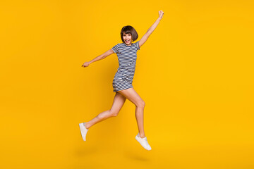 Fototapeta na wymiar Full body photo of funny brunette millennial lady jump wear dress sneakers isolated on yellow background
