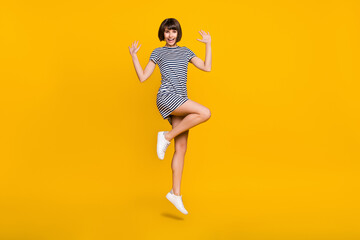 Full body photo of cool young lady jump wear striped dress sneakers isolated on yellow background