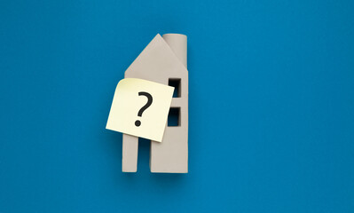 A question mark on a model house. Selection of real estate, assistance and advice when buying.