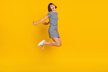 Fototapeta na wymiar Full length photo of nice brunette millennial lady jump wear dress sneakers isolated on yellow background