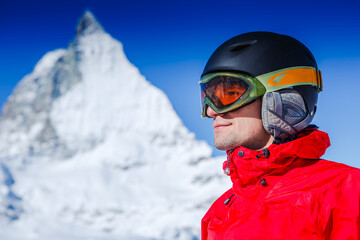Fototapeta na wymiar Happy man snowboarder posing with mountain landscape
