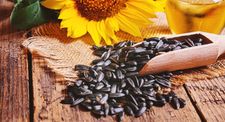 Sunflower seeds and oil bottle on old wooden background. Selective focus.