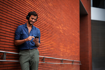 Young man listening to music. Urban fashion man with headphones enjoying the city © Jelena