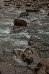 Mountain river among stones fell off rocks. Moody image. Fall colors. Nature autumn background.