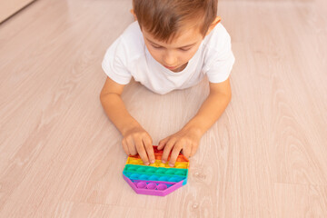 A child with a colorful pop it game. Anti-stress. Popular Relaxing rhomb shape silicone stress relief toy. Games for children