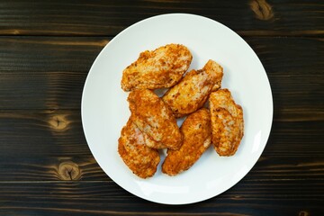 Raw chicken in white plate on wooden table.