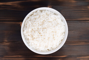 Bowl of cooked rice top view on wooden board.
