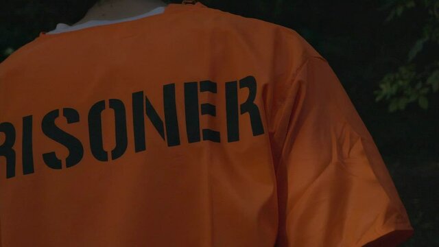 Low shot of prisoner walking in forest and looking