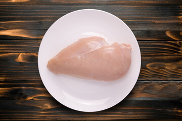 Raw chicken in plate on wooden table.