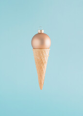 Creative arrangement made of an ice cream cone and Christmas bauble on a blue background. Minimal New Year concept. Summer Christmas inspiration.