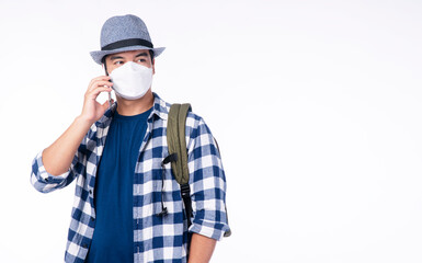 Lifestyle travel new normal safety concept. Traveler young man wear shirt, hat and face mask with backpack protect outbreak talking with smartphone while standing over isolated white background.