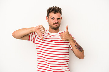 Young caucasian man isolated on white background showing thumbs up and thumbs down, difficult...