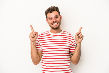 Young caucasian man isolated on white background indicates with both fore fingers up showing a...