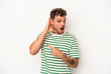 Fototapeta premium Young caucasian man isolated on white background trying to listening a gossip.