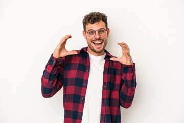 Naklejka premium Young caucasian man isolated on white background holding something with palms, offering to camera.