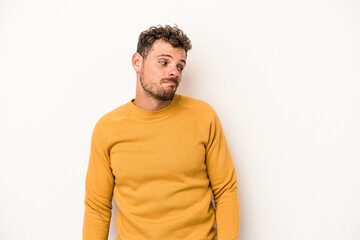 Young caucasian man isolated on white background shrugs shoulders and open eyes confused.