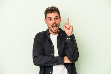 Young caucasian man isolated on green background having some great idea, concept of creativity.