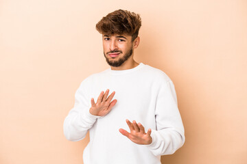Young arab man isolated on beige background rejecting someone showing a gesture of disgust.
