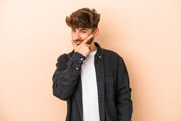 Young arab man isolated on beige background contemplating, planning a strategy, thinking about the way of a business.